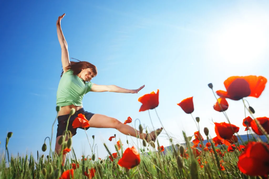 Happy girl jumping in poppy field